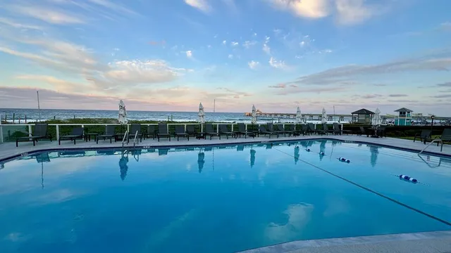 a view of a swimming pool with lawn chairs and a fire pit