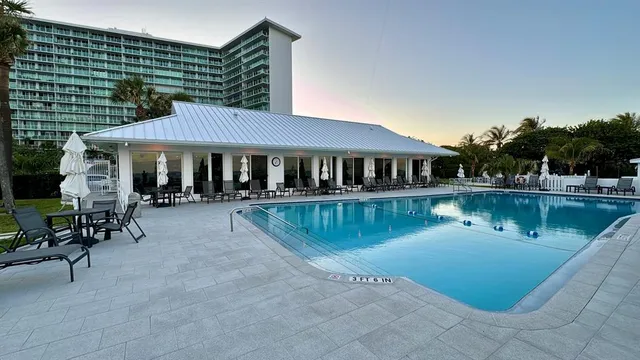 a view of a field with an ocean and trees in the background