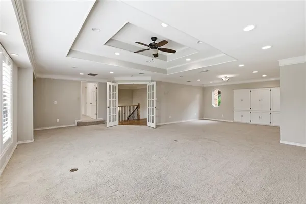 an empty room with chandelier fan and windows