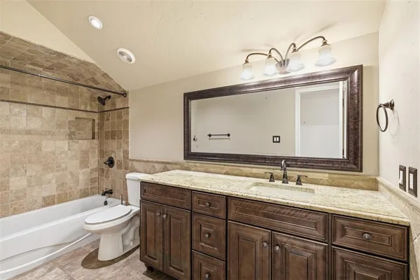 a bathroom with a granite countertop sink toilet a mirror and bathtub