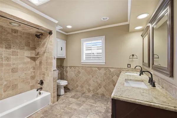 a bathroom with a granite countertop sink a toilet a bathtub and shower