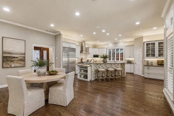 a dining hall with stainless steel appliances kitchen island granite countertop a dining table chairs and view living room