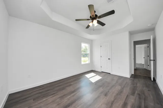 a view of empty room with wooden floor and ceiling fan