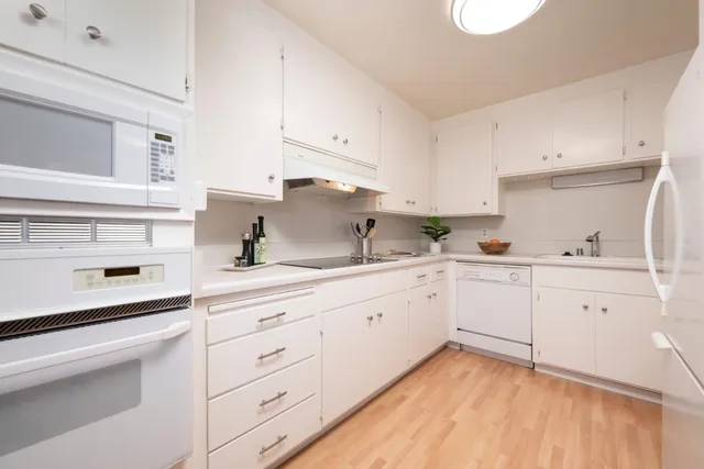 a kitchen with granite countertop white cabinets white appliances and a sink