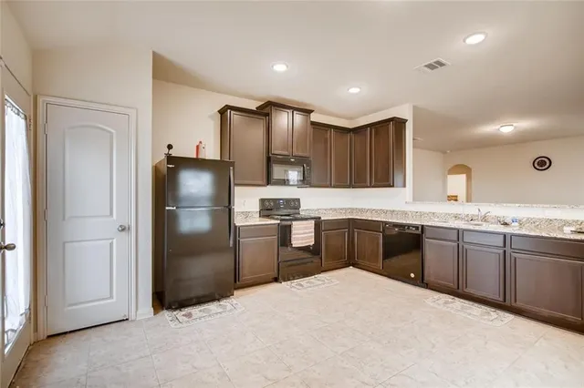 a kitchen with granite countertop stainless steel appliances cabinets a sink and a refrigerator