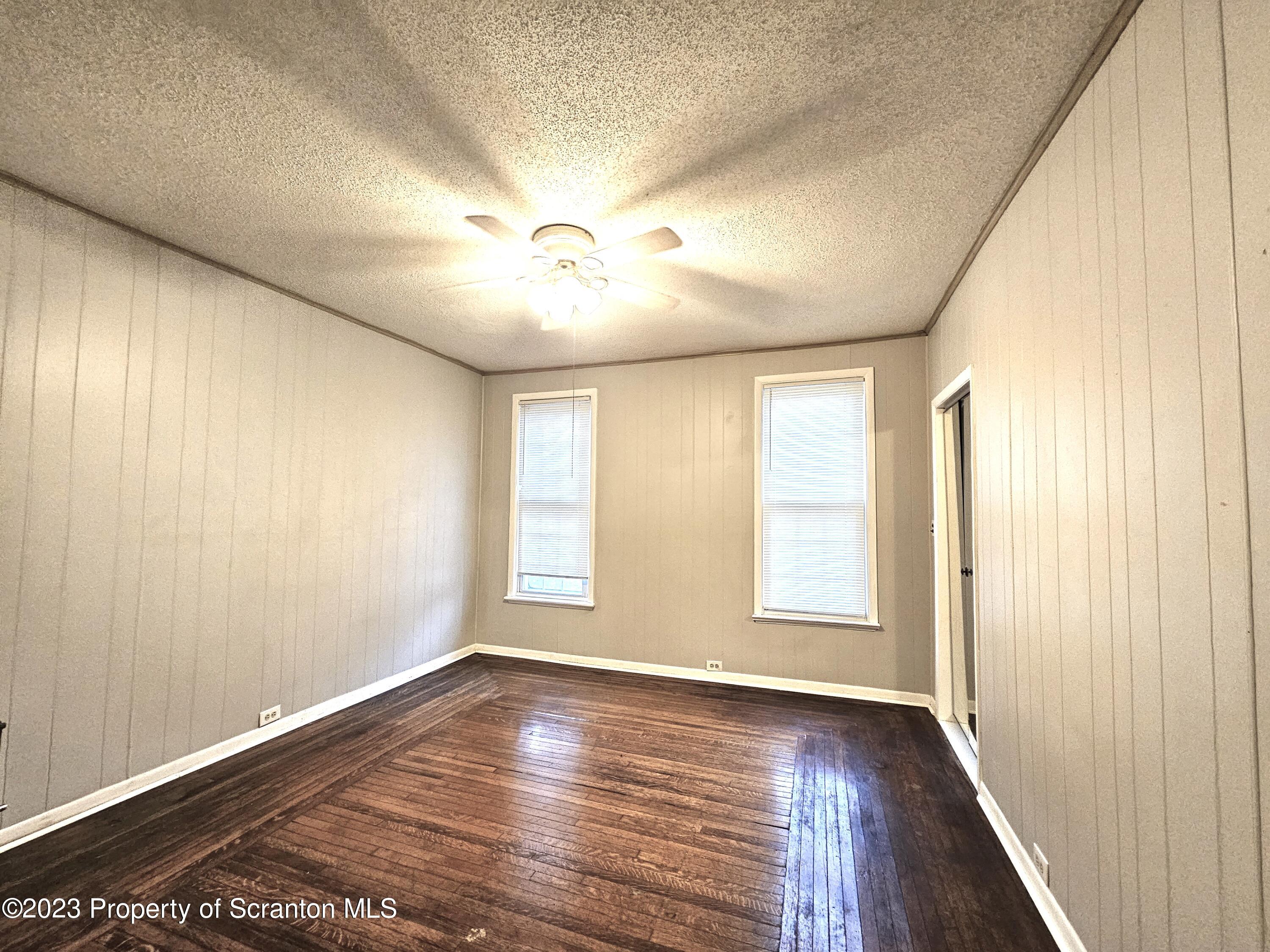 828 Cedar Avenue Scranton, PA 18505 - Photo 11 of 13 an empty room with wooden floor and windows