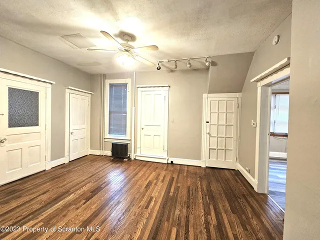 a view of an empty room with wooden floor and a window