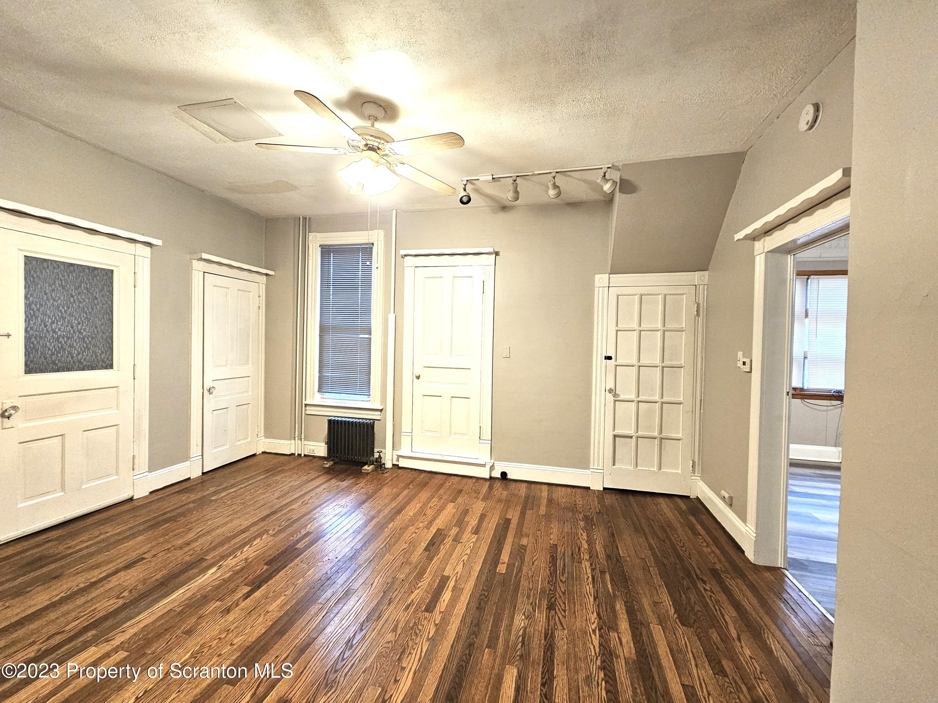 828 Cedar Avenue Scranton, PA 18505 - Photo 5 of 13 a view of an empty room with wooden floor and a window
