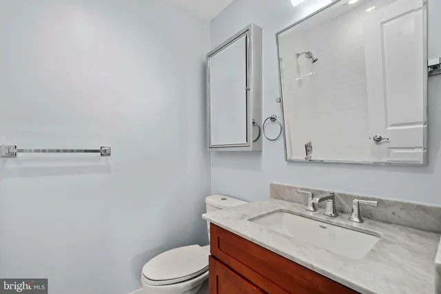 a bathroom with a granite countertop toilet sink and mirror