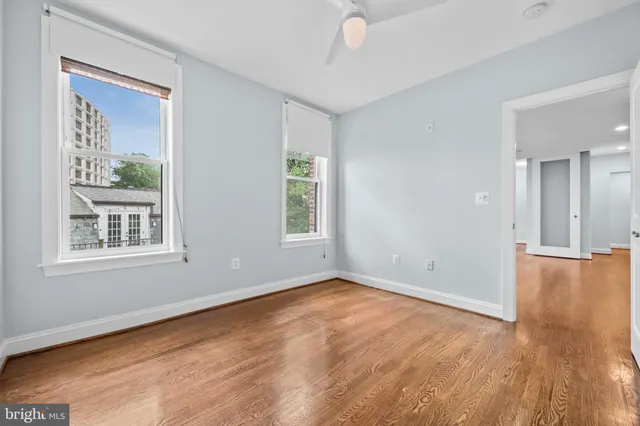 a view of an empty room with wooden floor and a window