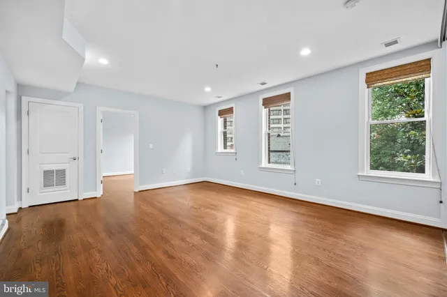 a view of an empty room with wooden floor and a window