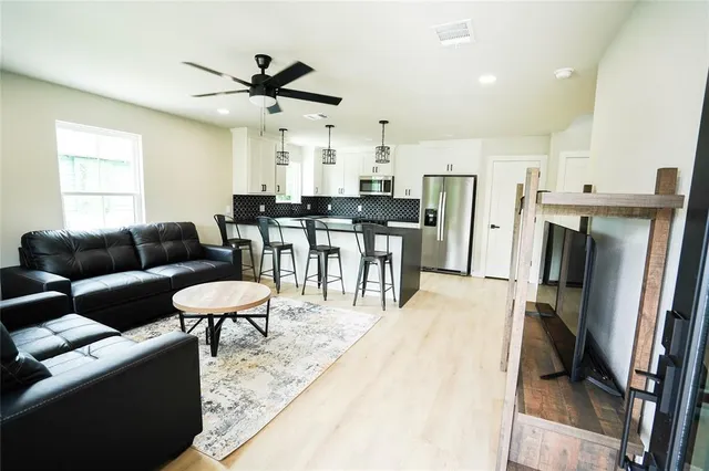 a living room with stainless steel appliances furniture a rug and a kitchen view