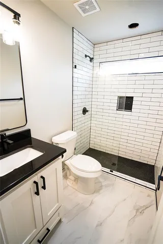 a bathroom with a granite countertop sink toilet and shower