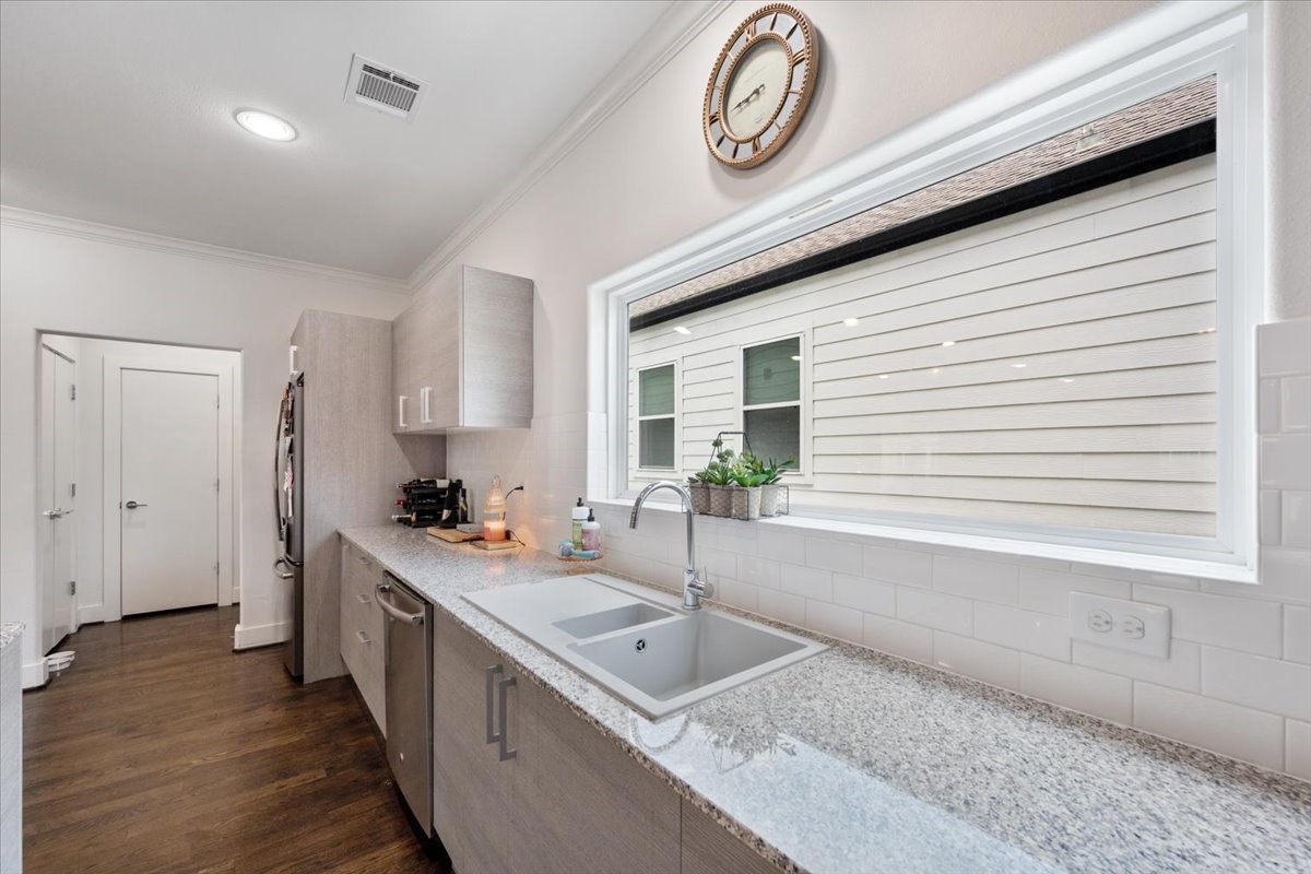 1333 West 22nd Street, Unit F Houston, TX 77008 - Photo 4 of 22 Bright kitchen with modern design featuring granite countertops, subway tile backsplash, and stainless steel appliances. Ample natural light from a large window above the sink, complemented by sleek cabinetry and hardwood floors.