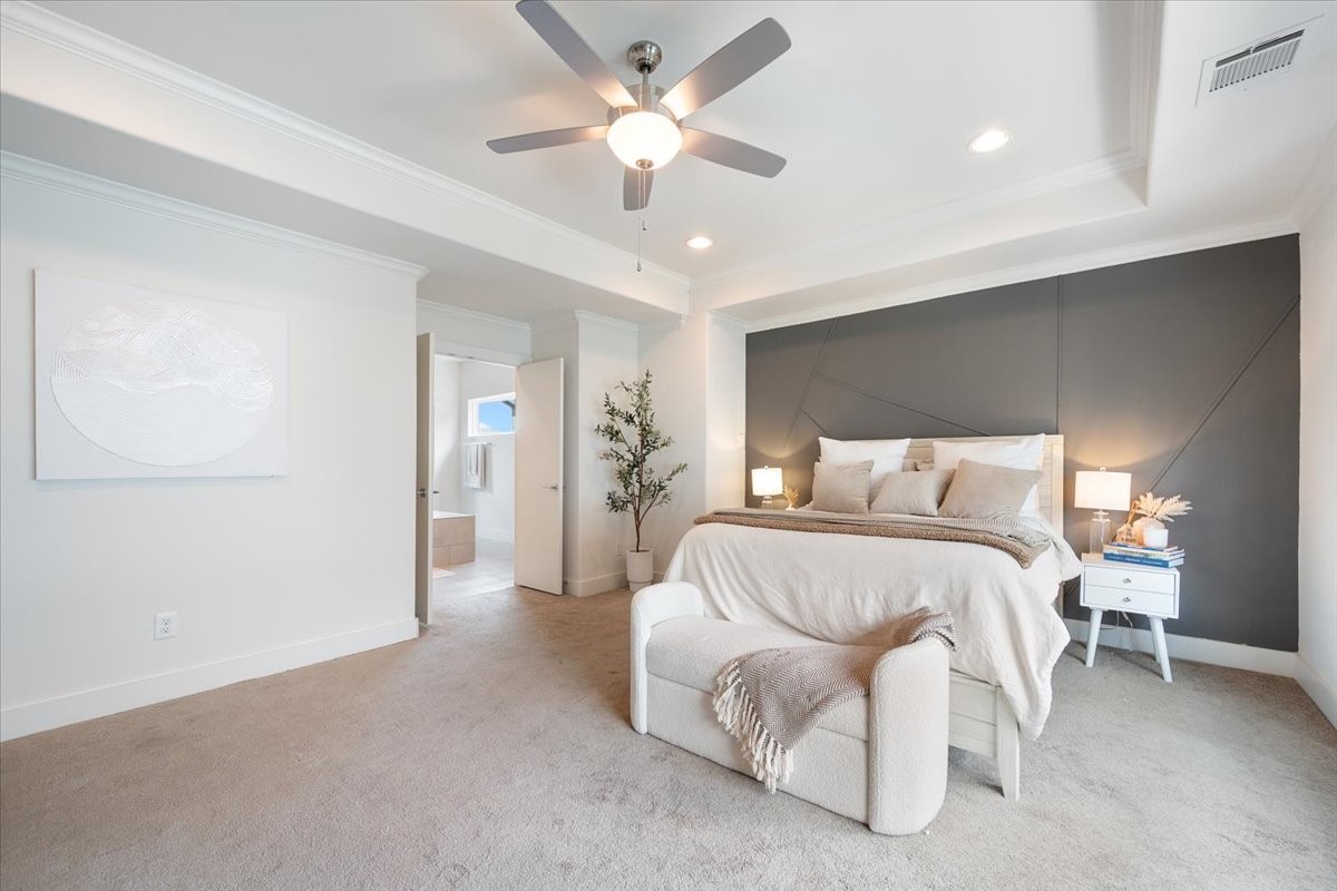 1333 West 22nd Street, Unit F Houston, TX 77008 - Photo 8 of 22 This spacious primary suite features a modern gray accent wall, complemented by elegant lighting. The room has access to an adjoining bathroom, enhancing convenience and functionality.