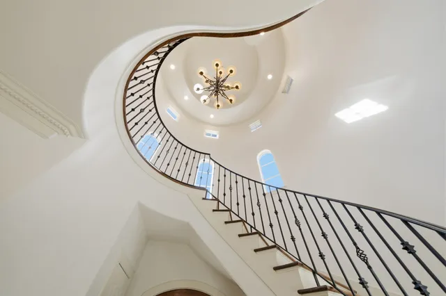 an empty room with a chandelier fan and windows