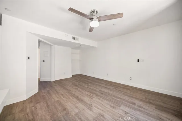 an empty room with wooden floor and ceiling fan