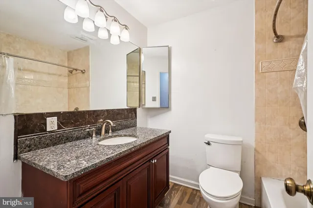 a bathroom with a granite countertop sink a toilet and mirror