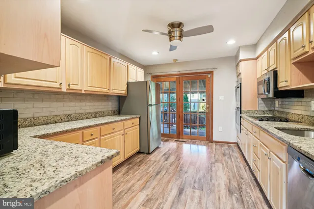a kitchen with stainless steel appliances granite countertop hardwood floor sink stove and wooden cabinets
