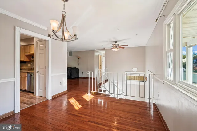 a view of a livingroom with wooden floor a ceiling fan and windows