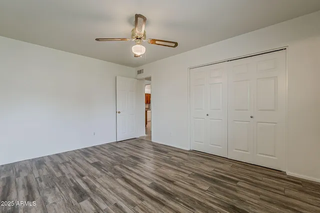 a view of empty room with wooden floor and fan