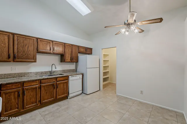 a kitchen with stainless steel appliances granite countertop a stove top oven a sink dishwasher and a refrigerator with wooden cabinets