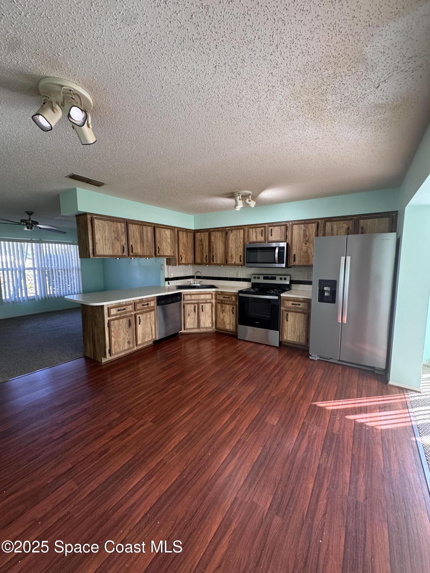 642 Altura Drive Cocoa, FL 32927 - Photo 5 of 13 a open kitchen with stainless steel appliances granite countertop a stove top oven a sink and dishwasher with wooden floor