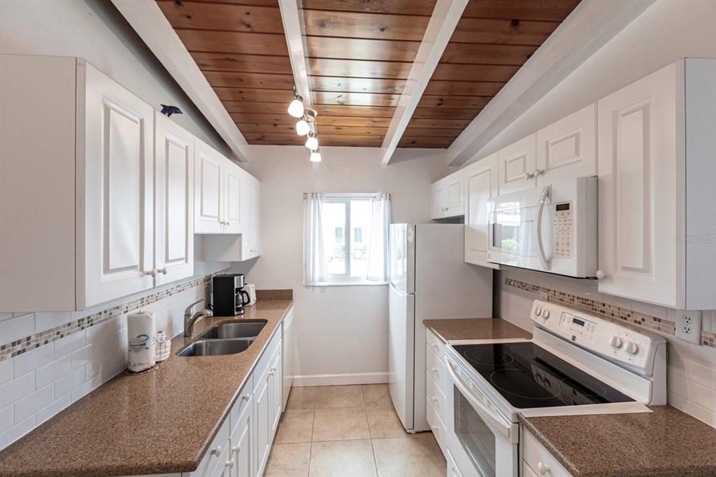 6006 Midnight Pass Road, Unit 5 Sarasota, FL 34242 - Photo 5 of 22 a kitchen with stainless steel appliances granite countertop a sink stove and cabinets