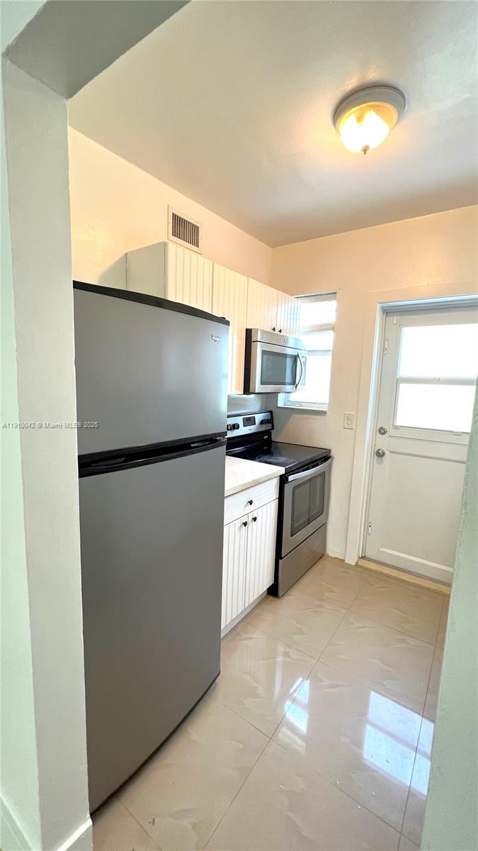 8235 Crespi Boulevard, Unit 1 Miami Beach, FL 33141 - Photo 11 of 24 a kitchen with stainless steel appliances a refrigerator and a stove