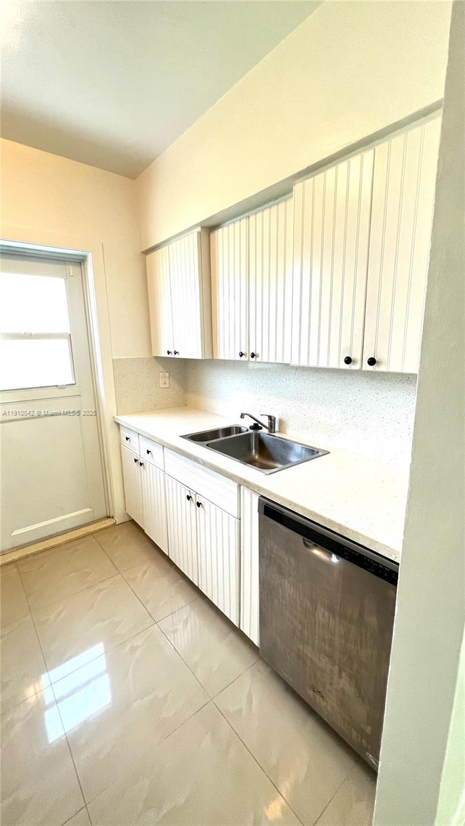 8235 Crespi Boulevard, Unit 1 Miami Beach, FL 33141 - Photo 10 of 24 a kitchen with granite countertop a sink a stove and cabinets