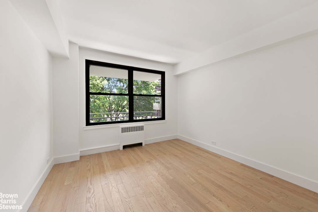 98-41 64th Road, Unit 3G Queens, NY 11374 - Photo 11 of 14 an empty room with wooden floor and windows