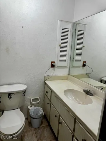 a bathroom with a granite countertop sink and a toilet