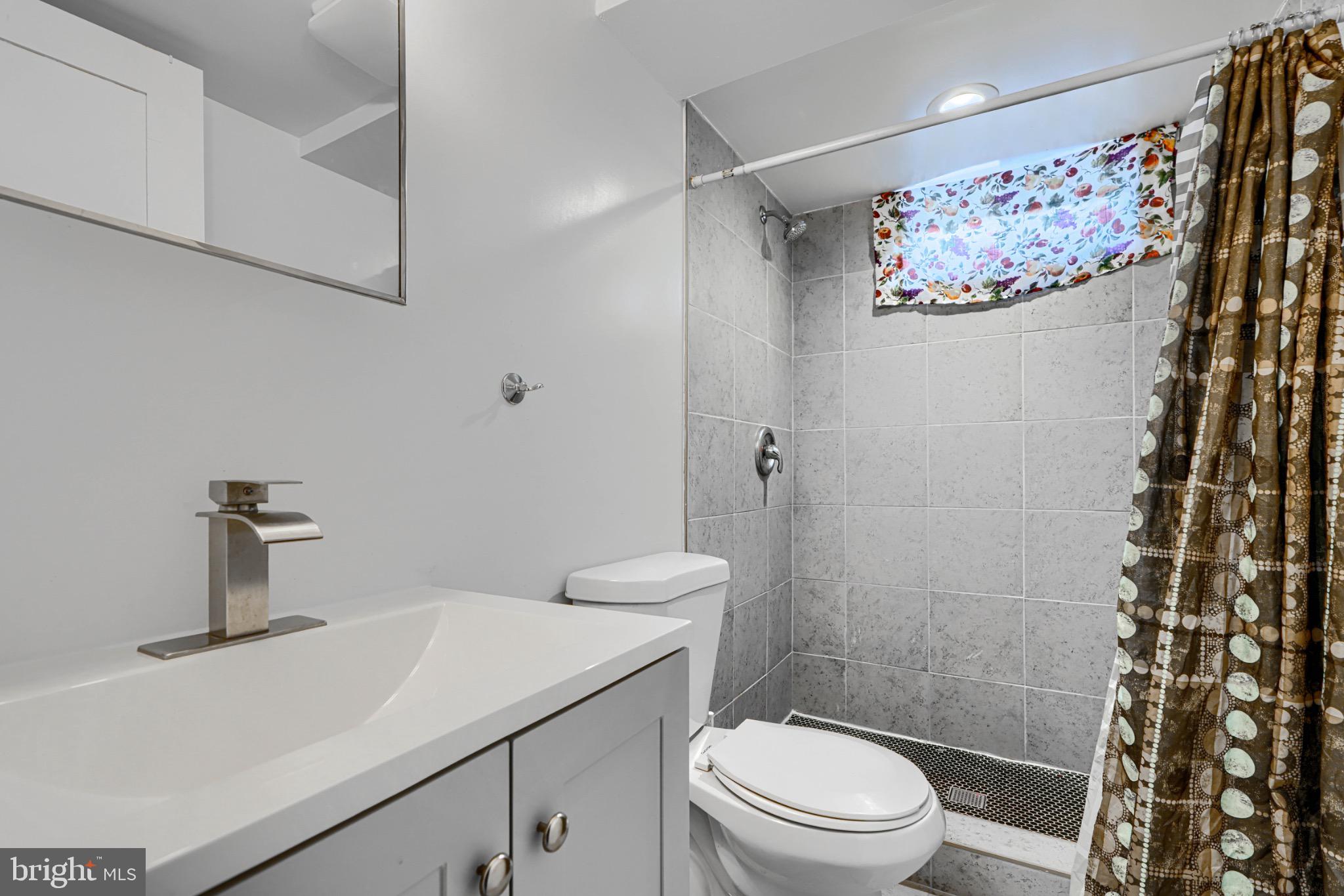 804 Quail Street Baltimore, MD 21224 - Photo 29 of 39 a bathroom with a sink a toilet and shower curtain