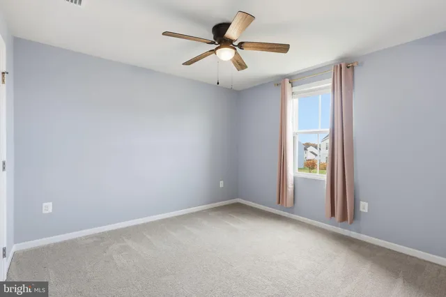 an empty room with window and ceiling fan