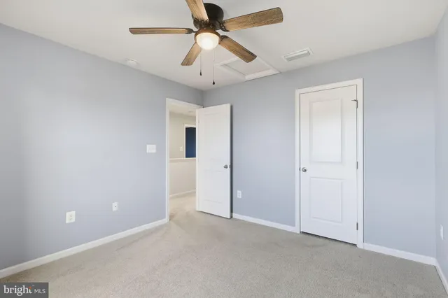an empty room with closet and a chandelier fan