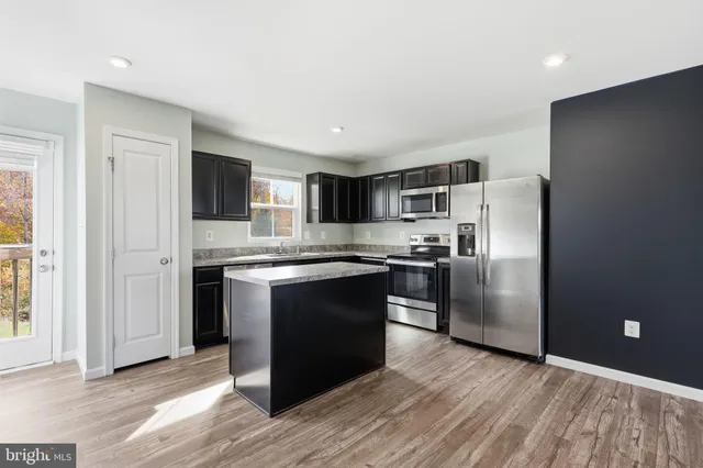 a kitchen with granite countertop a refrigerator and a stove top oven