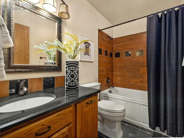 a bathroom with a granite countertop sink a toilet and shower
