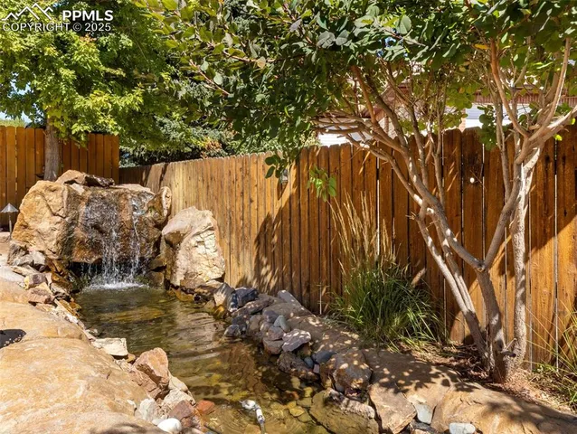 a view of backyard with wooden fence and trees