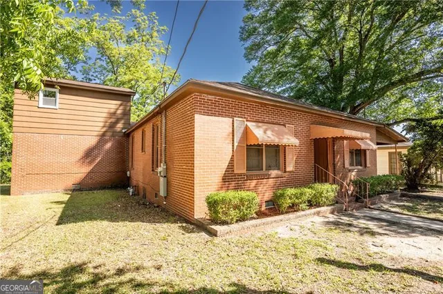 a backyard of a house with potted plants and large tree