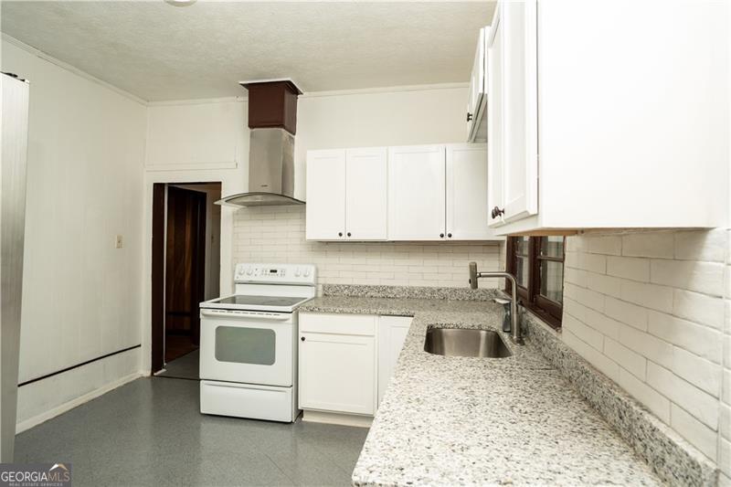 305 Wolfe Street Dublin, GA 31021 - Photo 7 of 27 a kitchen with a stove and white cabinets