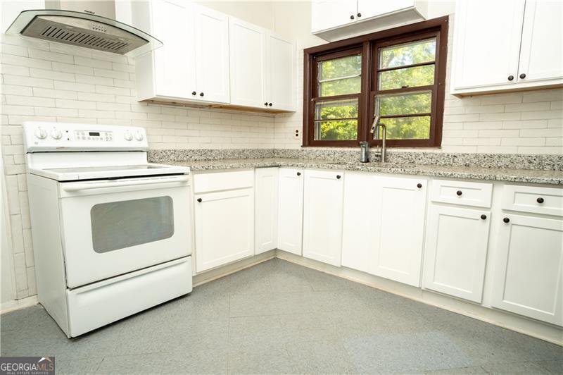 305 Wolfe Street Dublin, GA 31021 - Photo 8 of 27 a kitchen with granite countertop white cabinets and white appliances