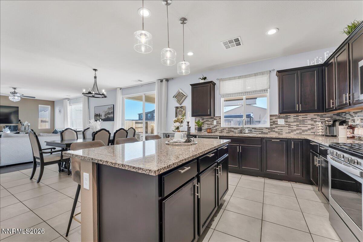 2139 Roaring Fork Court Sparks, NV 89436 - Photo 11 of 42 a open kitchen with stainless steel appliances granite countertop a kitchen island a stove a sink a dining table and chairs