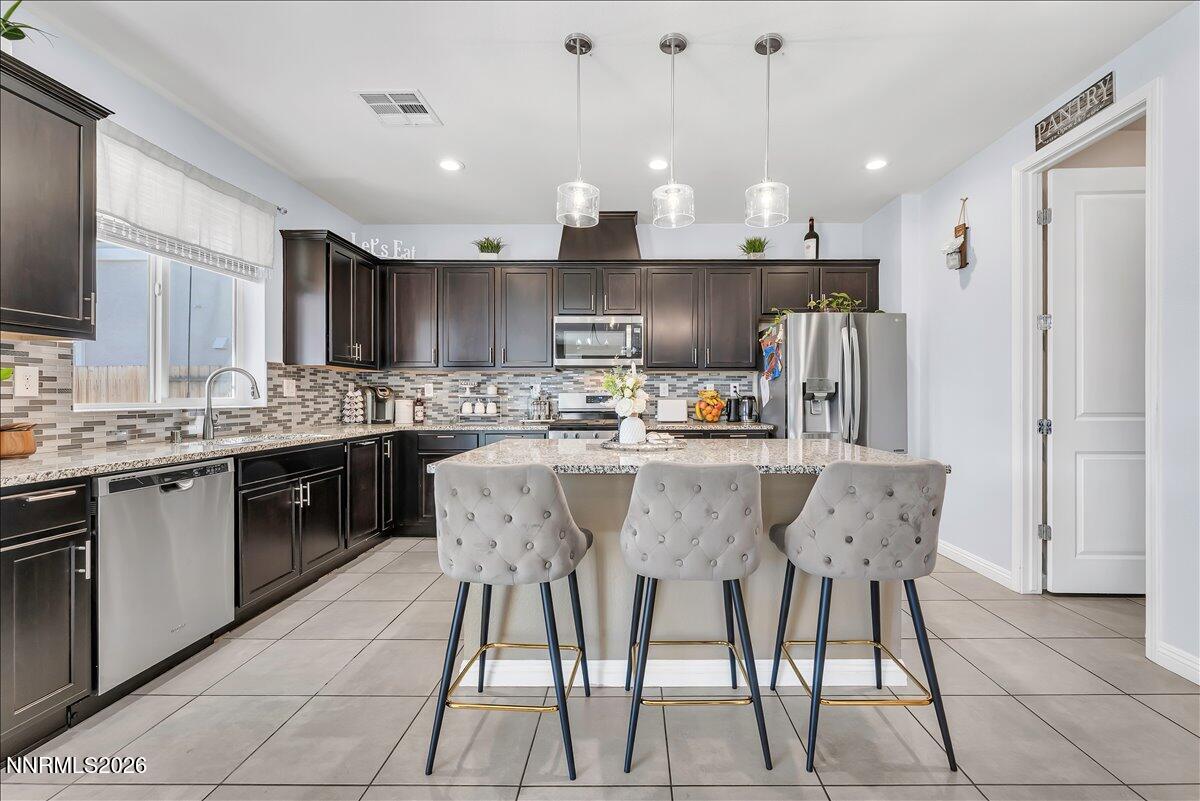 2139 Roaring Fork Court Sparks, NV 89436 - Photo 9 of 42 a kitchen with stainless steel appliances kitchen island granite countertop a sink a stove a refrigerator cabinets and chairs