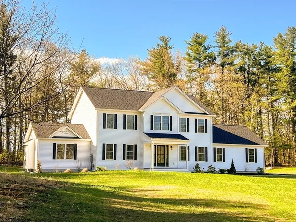 a front view of a house with a yard and trees