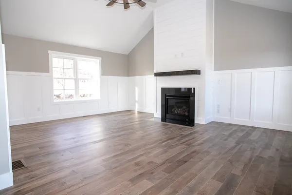 an empty room with wooden floor fireplace and windows