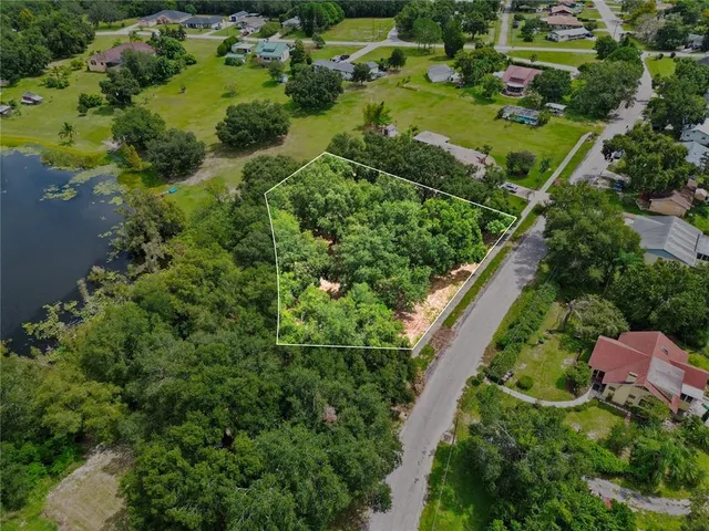 an aerial view of residential house with outdoor space and trees all around