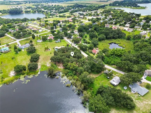 an aerial view of residential houses with outdoor space and trees