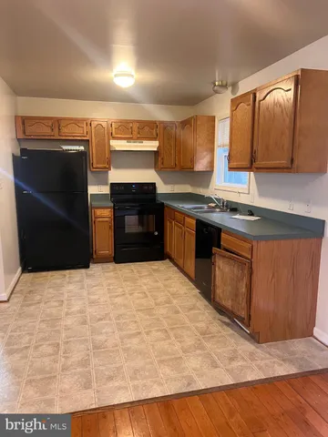 a large kitchen with kitchen island granite countertop wooden cabinets a refrigerator and a sink