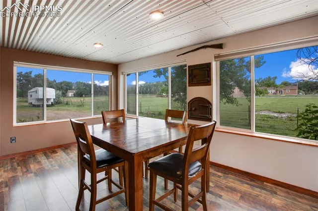 a dining room with furniture large windows and wooden floor
