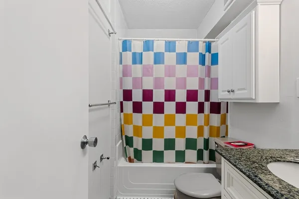a bathroom with a granite countertop toilet a sink and a mirror